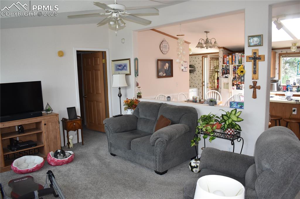 Image 23 of 47: Carpeted living area featuring a chandelier and ceiling fan