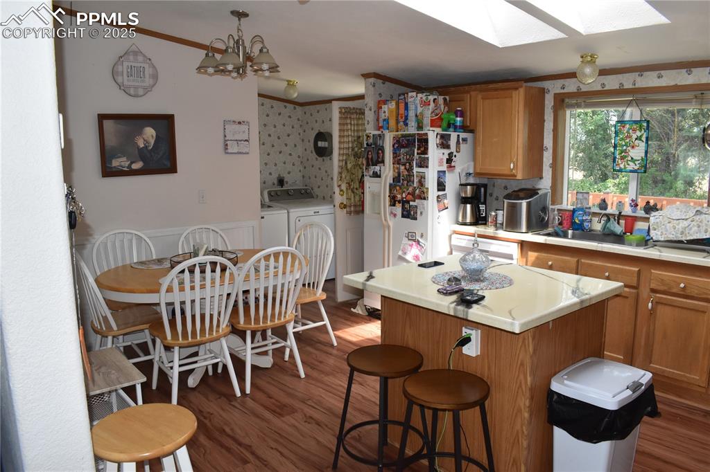 Image 24 of 47: Kitchen with brown cabinets, light countertops, white refrigerator with ice