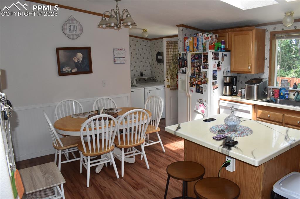 Image 25 of 47: Kitchen with light countertops, a kitchen island, white appliances, brown c