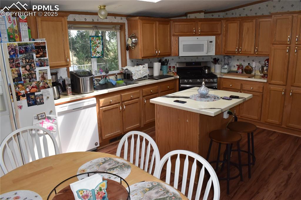 Image 26 of 47: Kitchen featuring light countertops, dark wood-type flooring, white applian