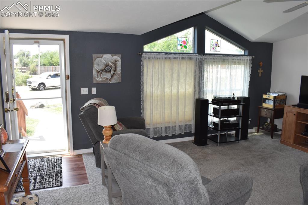 Image 39 of 47: Living area with carpet flooring, vaulted ceiling, and a ceiling fan