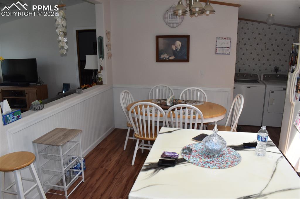 Image 41 of 47: Dining space featuring a chandelier, dark wood finished floors, a wainscote