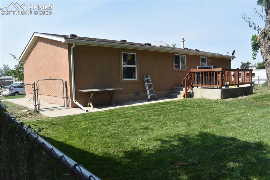 Image 9 of 47: Rear view of house featuring a gate, crawl space, stucco siding, a patio ar