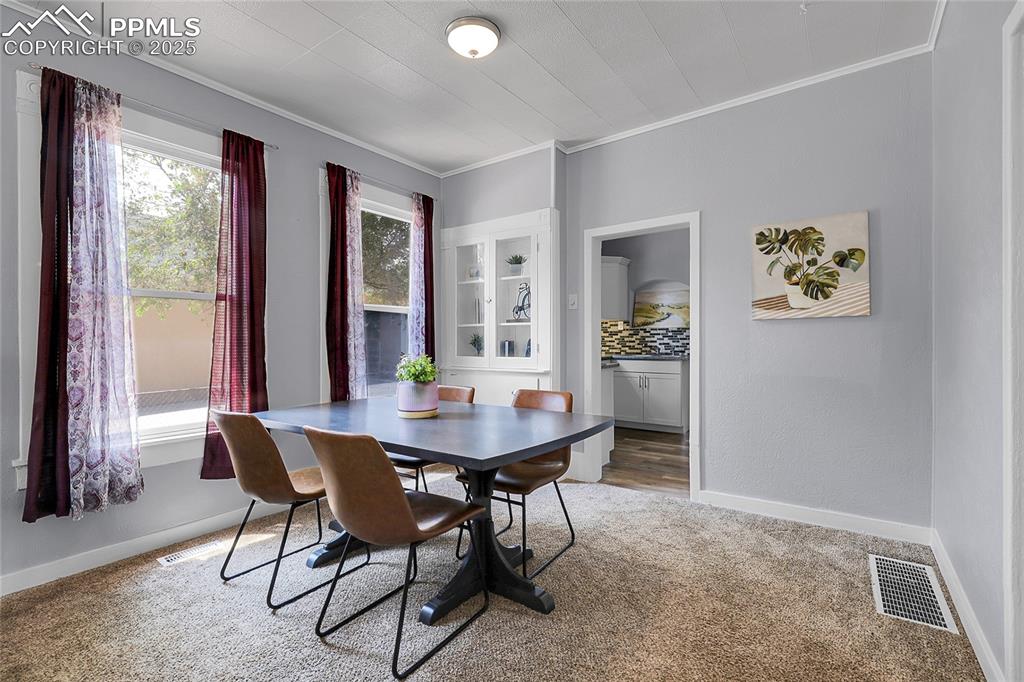 Image 10 of 29: Carpeted dining space featuring baseboards and crown molding