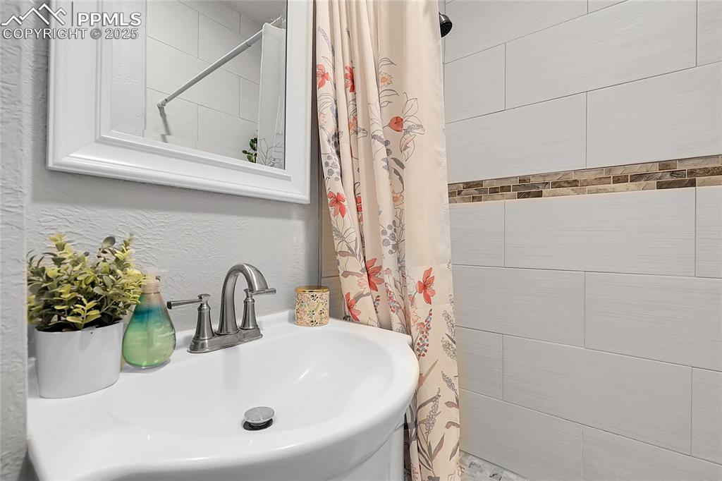 Image 13 of 29: Bathroom with a sink and tiled shower
