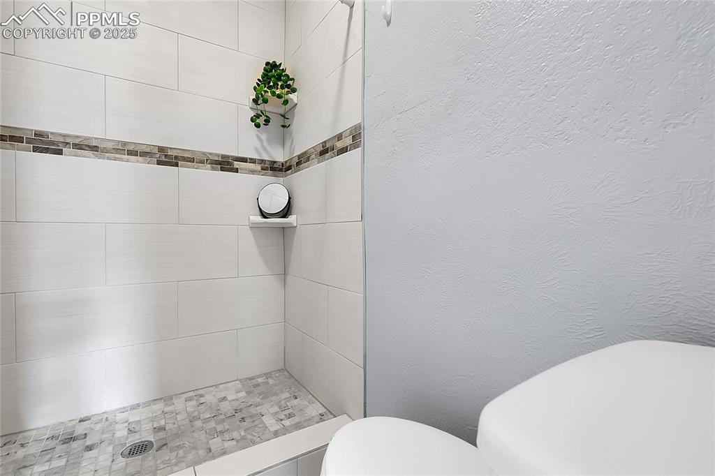 Image 14 of 29: Full bathroom featuring a textured wall and a tile shower