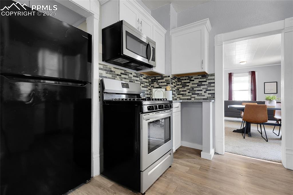 Image 18 of 29: Kitchen with stainless steel appliances, tasteful backsplash, white cabinet