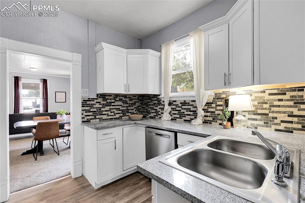 Image 19 of 29: Kitchen with plenty of natural light, stainless steel dishwasher, and white