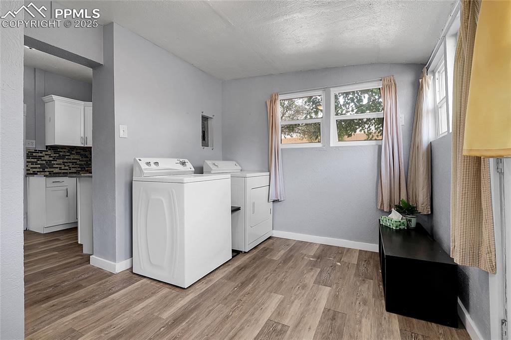 Image 21 of 29: Washroom featuring washing machine and clothes dryer, light wood-style floo
