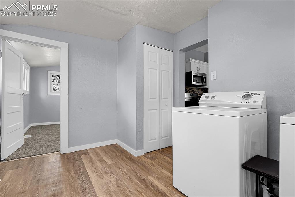 Image 22 of 29: Laundry area featuring washer / clothes dryer, light wood-type flooring, an