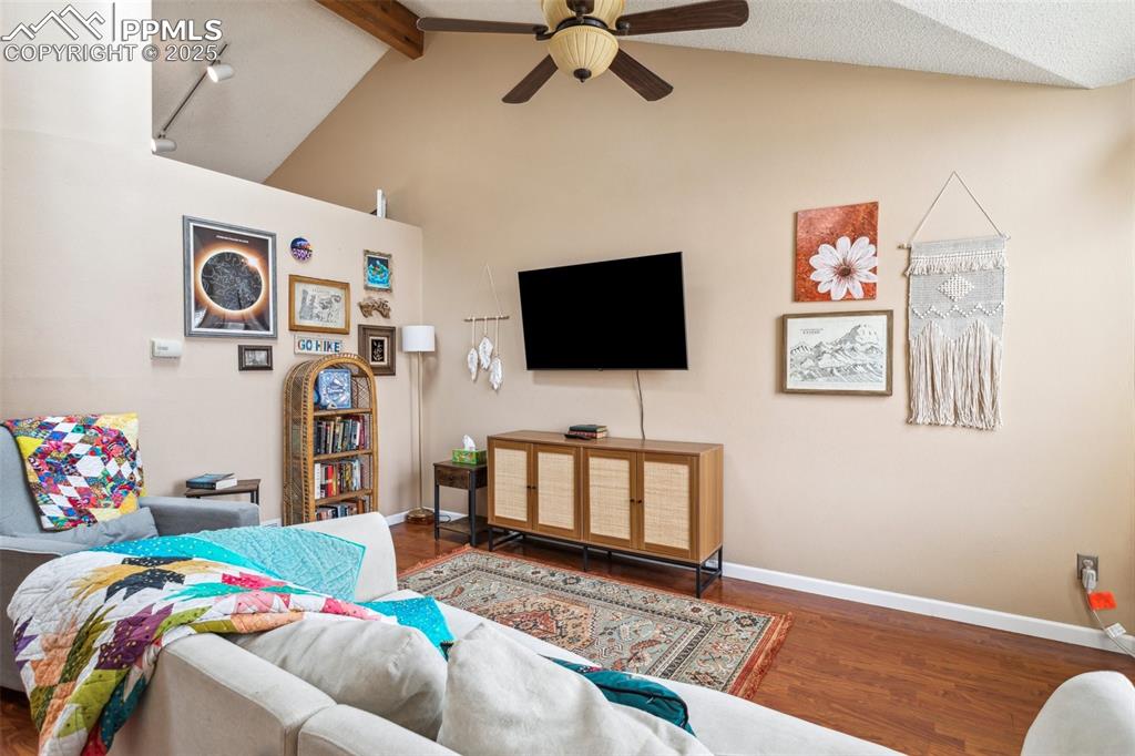 Image 12 of 35: Living room featuring vaulted ceiling with beams, baseboards, ceiling fan,