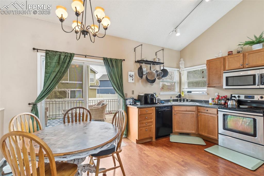 Image 13 of 35: Kitchen featuring dark countertops, a sink, a notable chandelier, stainless