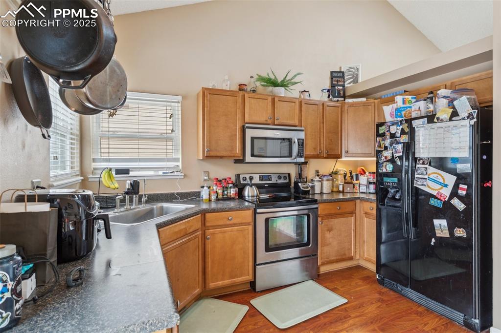 Image 14 of 35: Kitchen featuring dark countertops, a sink, lofted ceiling, stainless steel