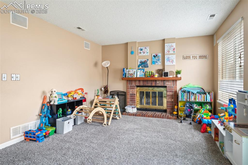 Image 16 of 35: Recreation room featuring carpet flooring, a textured ceiling, and visible