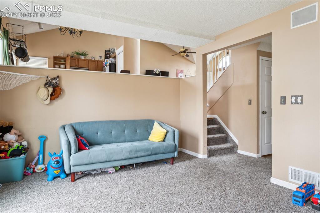 Image 18 of 35: Sitting room featuring stairs, a ceiling fan, visible vents, and carpet