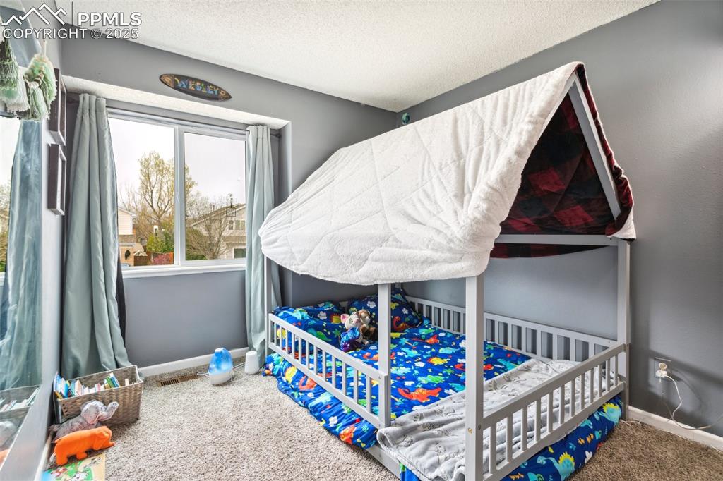 Image 29 of 35: Carpeted bedroom with baseboards and a textured ceiling