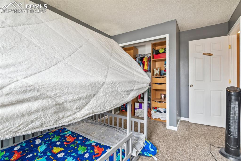 Image 30 of 35: Bedroom with a closet, carpet flooring, and a textured ceiling