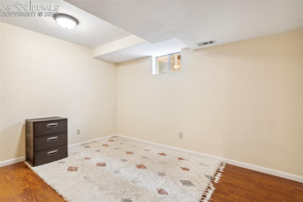 Image 31 of 35: Below grade area with visible vents, baseboards, and wood finished floors
