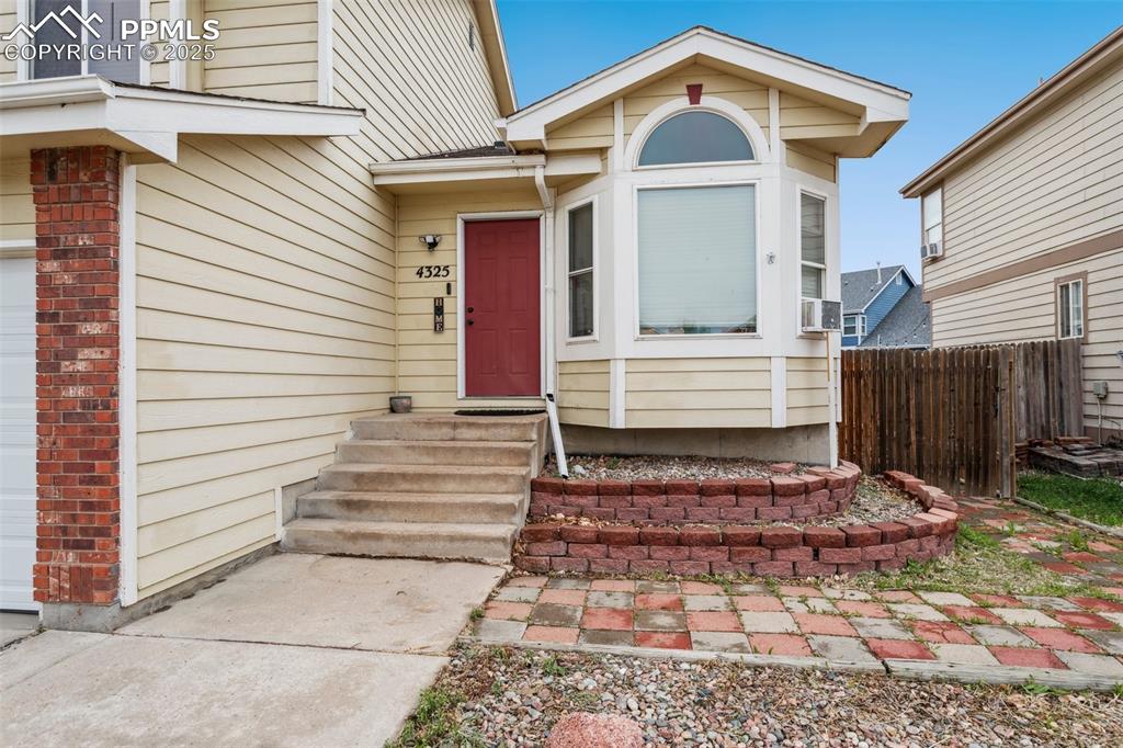 Image 9 of 35: View of exterior entry with brick siding, fence, and cooling unit