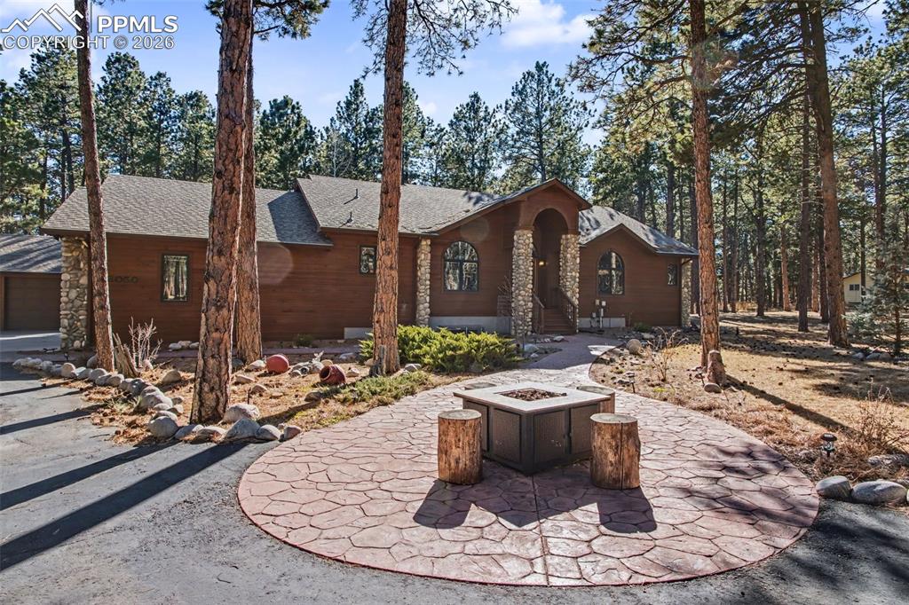 Caption: Chalet / cabin with an outdoor fire pit, roof with shingles, and a garage
