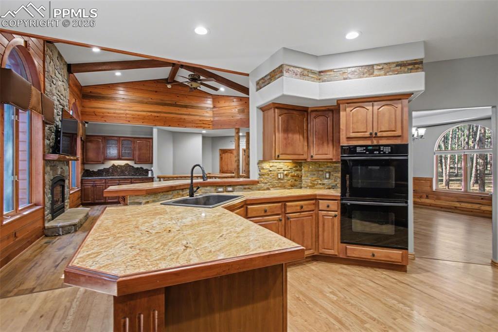 Image 15 of 50: Kitchen with a peninsula, wood finish cabinetry, lofted ceiling, light wood