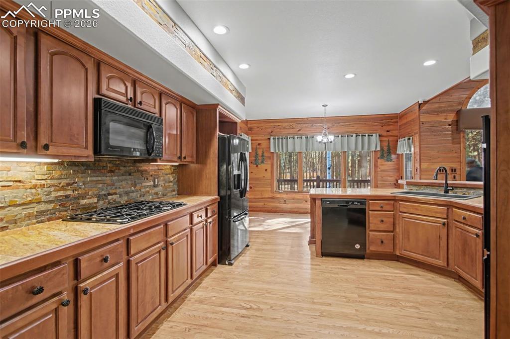 Image 16 of 50: Kitchen with light countertops, black appliances, light wood-style flooring
