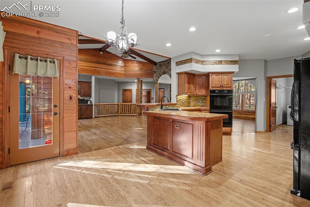 Image 18 of 50: Kitchen featuring light wood-type flooring, a chandelier, black appliances,