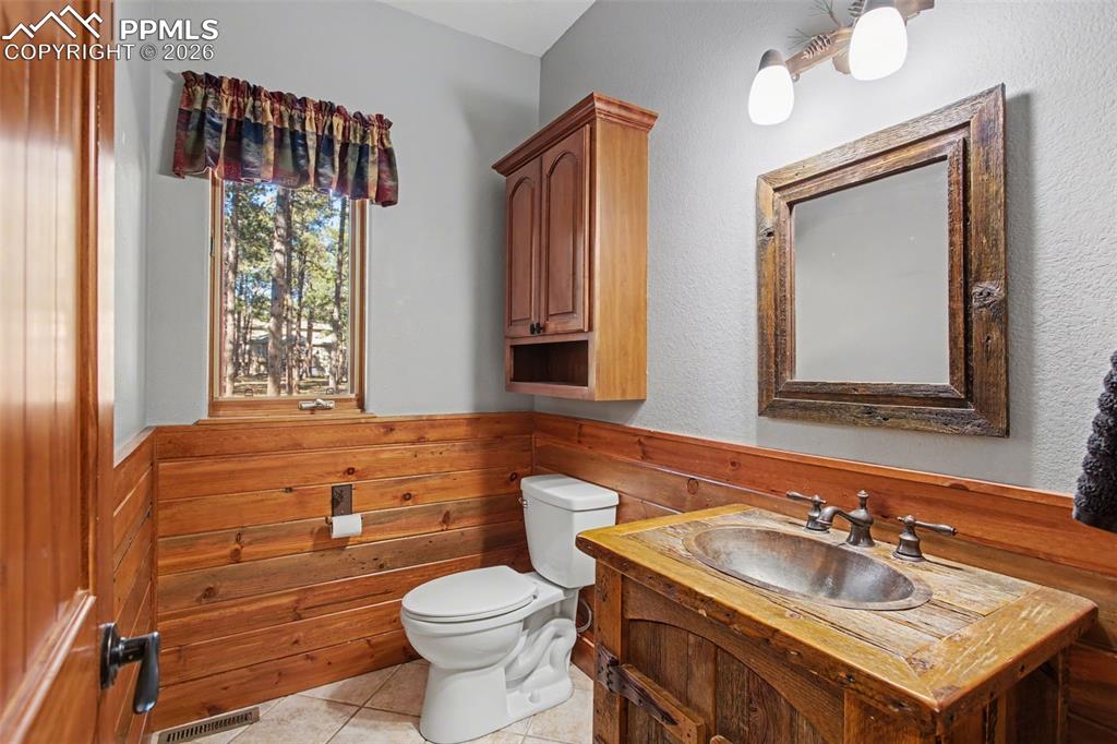 Image 22 of 50: Bathroom featuring vanity, a wainscoted wall, wooden walls, and light tile 
