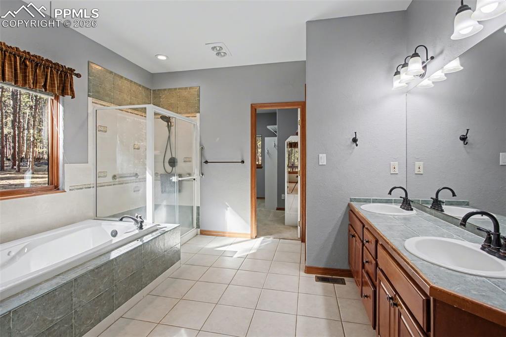 Image 26 of 50: Bathroom with a stall shower, double vanity, light tile patterned floors, a