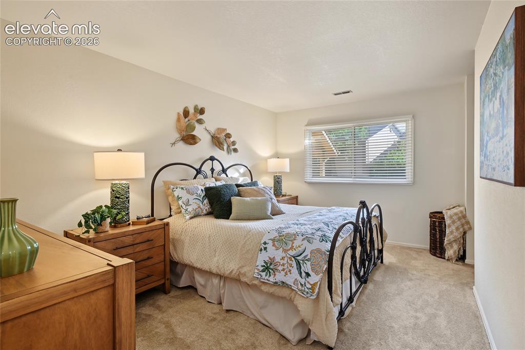 Image 19 of 27: Carpeted bedroom featuring a window with blinds, light-colored walls, and a