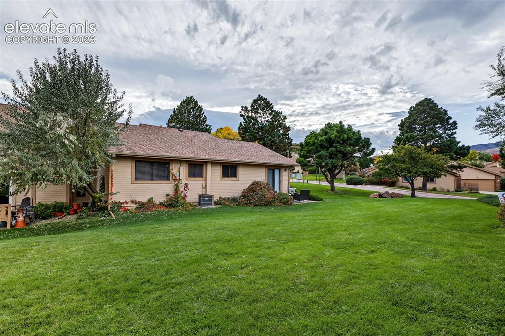 Image 26 of 27: Expansive green lawn with mature trees and a single-story residence featuri
