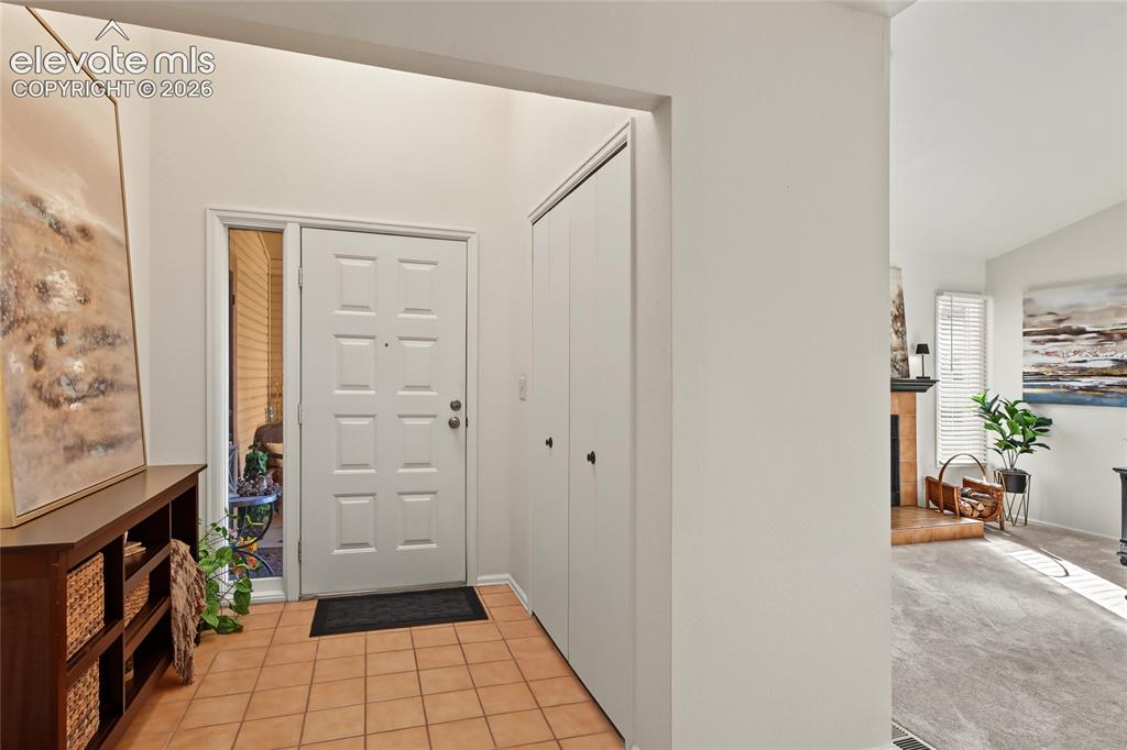 Image 5 of 27: Tiled entry with high ceilings, paneled entry door, and bi-fold closet door