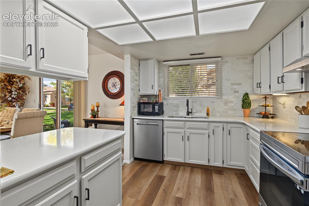 Image 8 of 27: Kitchen featuring white shaker-style cabinetry, stainless steel appliances,