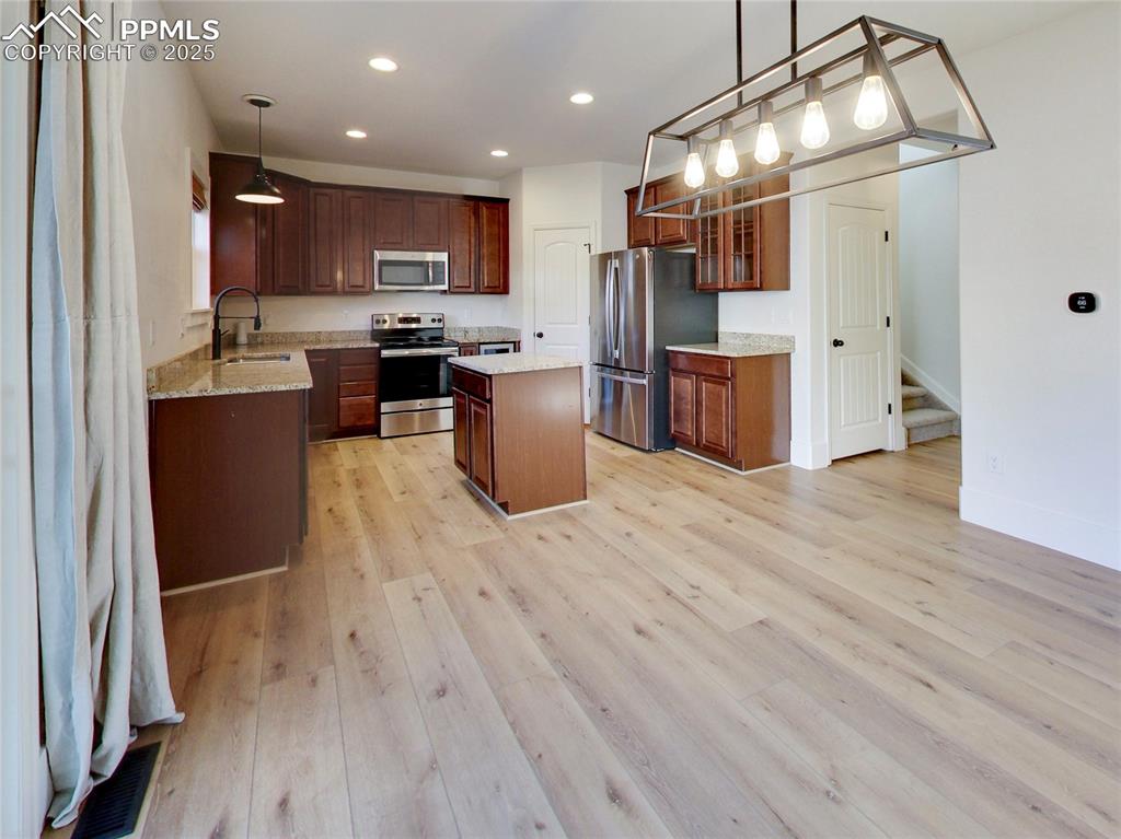 Image 11 of 37: Kitchen with stainless steel appliances, pendant lighting, a center island,