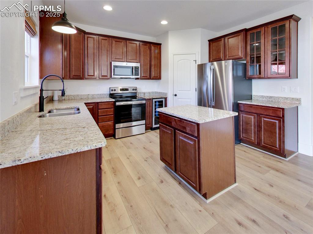 Image 15 of 37: Kitchen with stainless steel appliances, beverage cooler, decorative light 