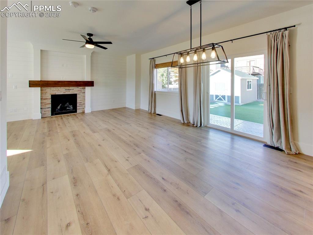 Image 17 of 37: Unfurnished living room with light wood-style floors, a stone fireplace, an