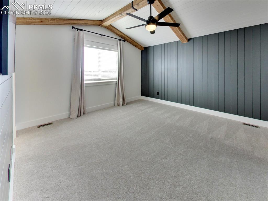 Image 18 of 37: Additional living space featuring light carpet, ceiling fan, and wood walls
