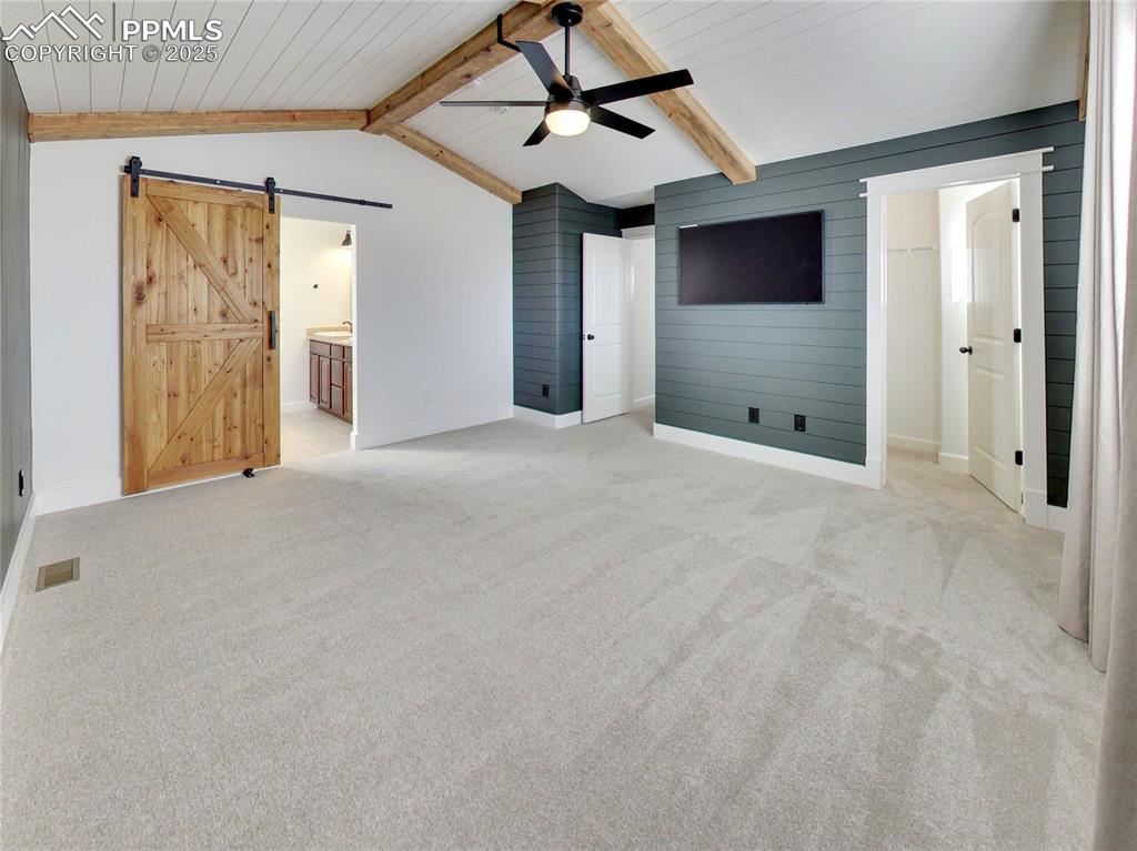 Image 19 of 37: Unfurnished bedroom with connected bathroom, a barn door, light colored car