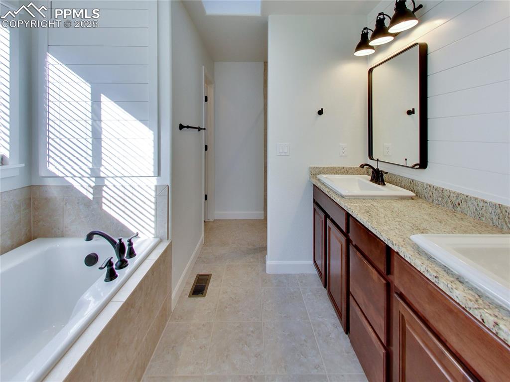 Image 20 of 37: Full bath with healthy amount of natural light, a bath, double vanity, and 