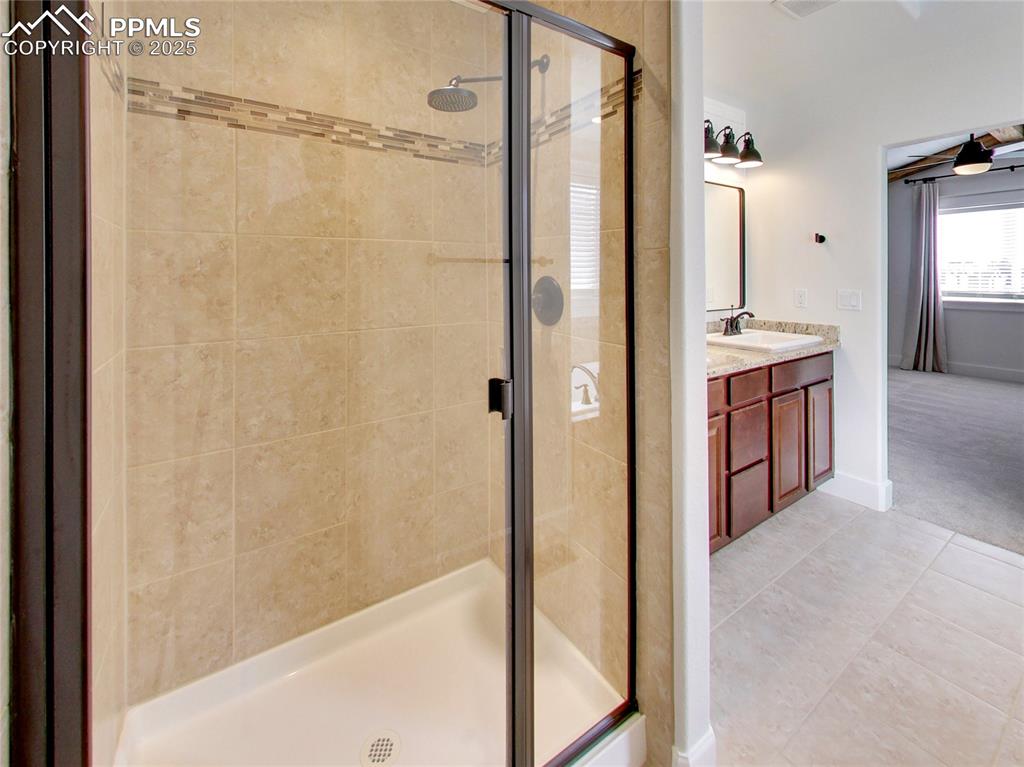Image 23 of 37: Bathroom featuring light tile patterned floors, a stall shower, and vanity