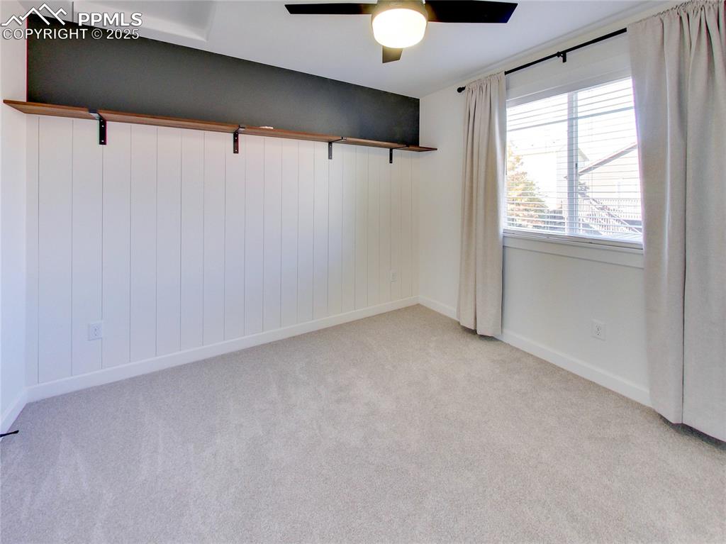 Image 24 of 37: Unfurnished room featuring light colored carpet, a ceiling fan, and wood wa
