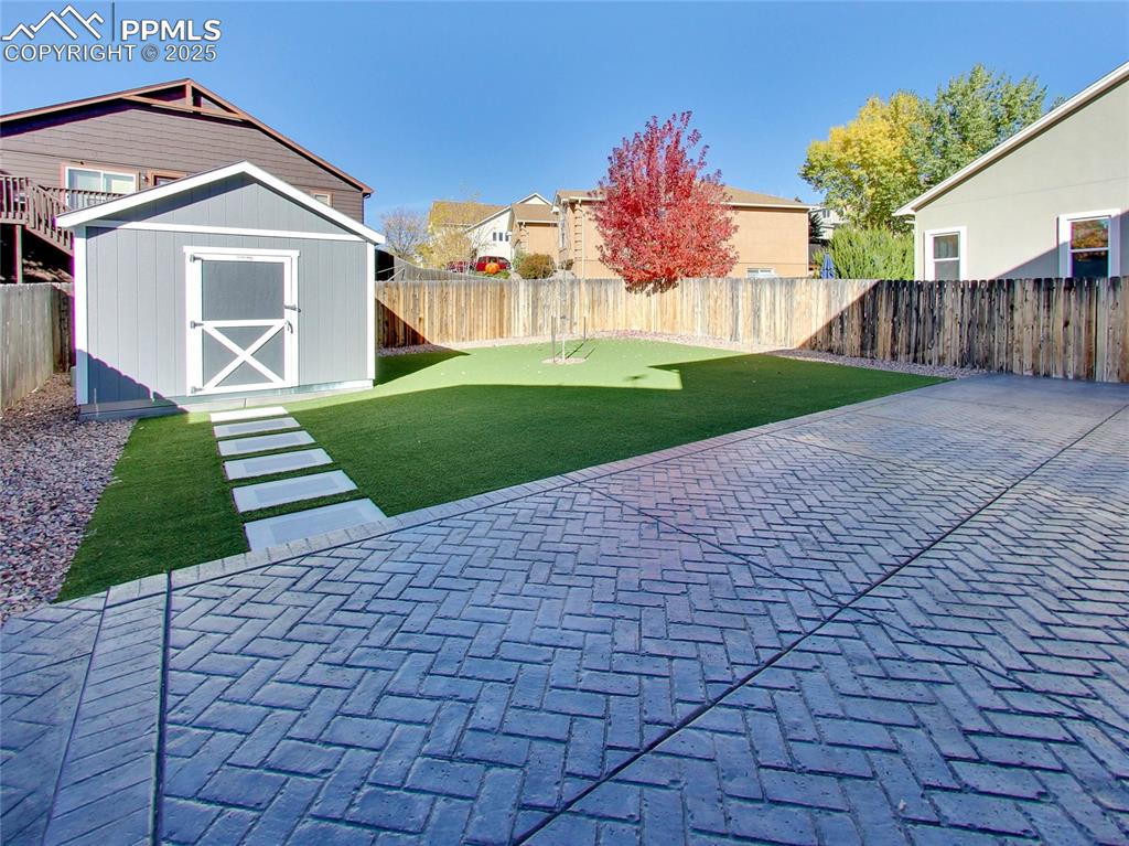Image 32 of 37: Fenced backyard featuring a storage unit