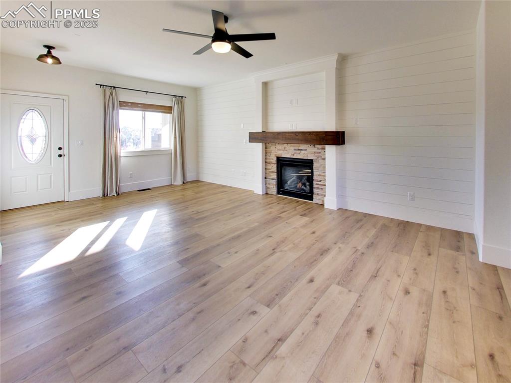 Image 6 of 37: Unfurnished living room with a fireplace, light wood finished floors, a cei