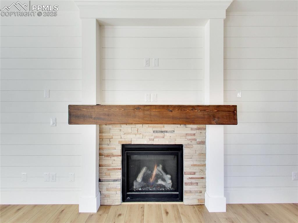 Image 7 of 37: Detailed view of wood finished floors, a warm lit fireplace, and wooden wal