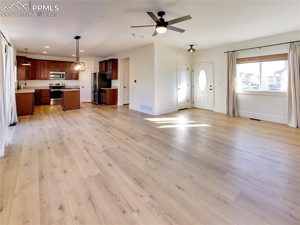 Image 9 of 37: Unfurnished living room with light wood-style flooring, a ceiling fan, and 