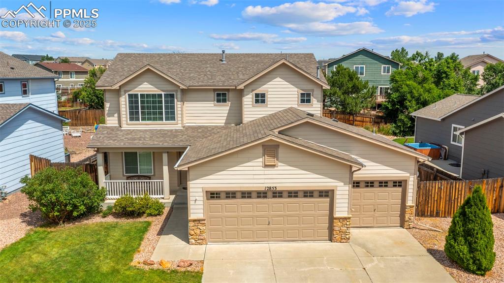 Caption: Traditional-style home featuring roof with shingles, stone siding, a residential view, and concrete 