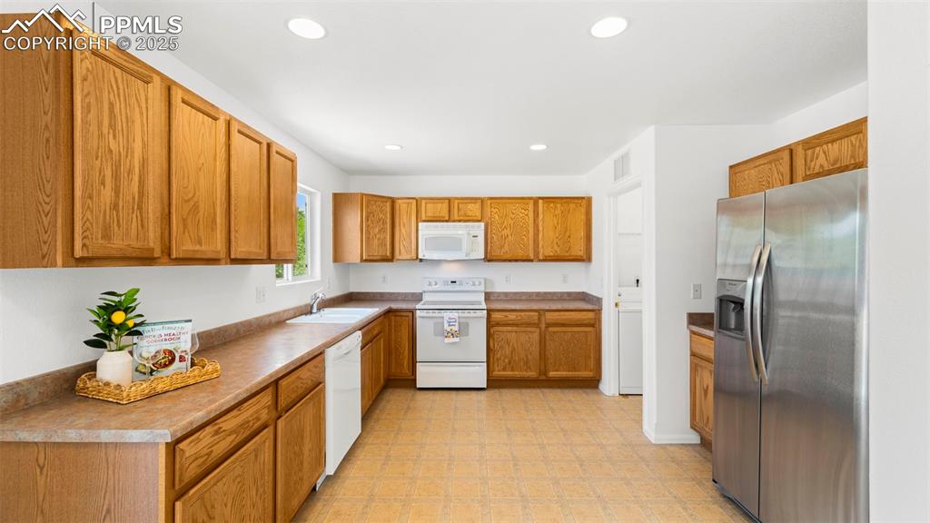 Image 11 of 46: Kitchen featuring white appliances, recessed lighting, light floors, and br