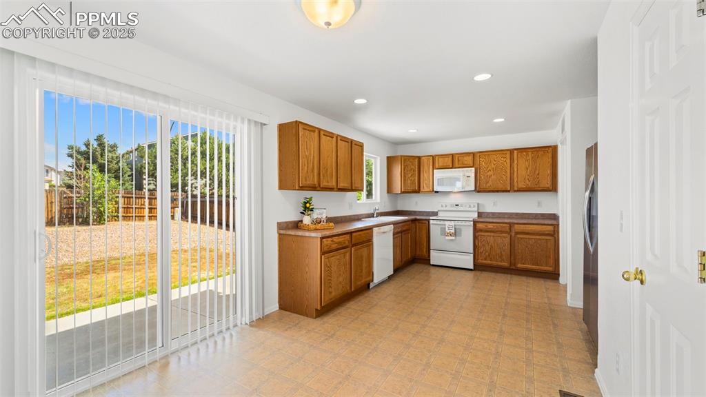 Image 12 of 46: Kitchen featuring brown cabinetry, appliances, recessed lighting, and light