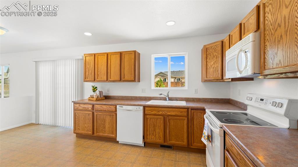 Image 13 of 46: Kitchen with appliances, brown cabinets, recessed lighting, and light floor