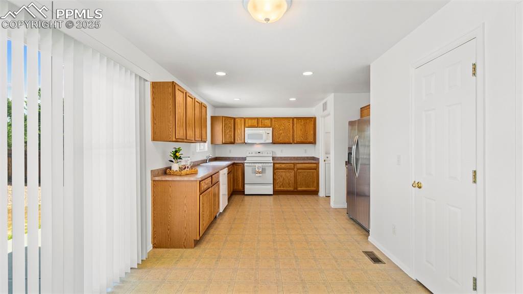 Image 14 of 46: Kitchen featuring appliances, brown cabinets, recessed lighting, light coun